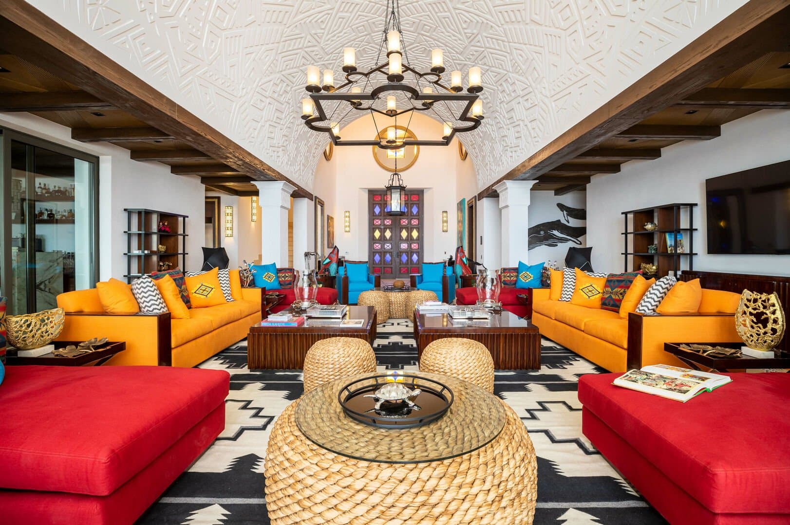 The colorful sitting area of this Los Cabos beachfront villa, filled with orange and red couches and chairs.