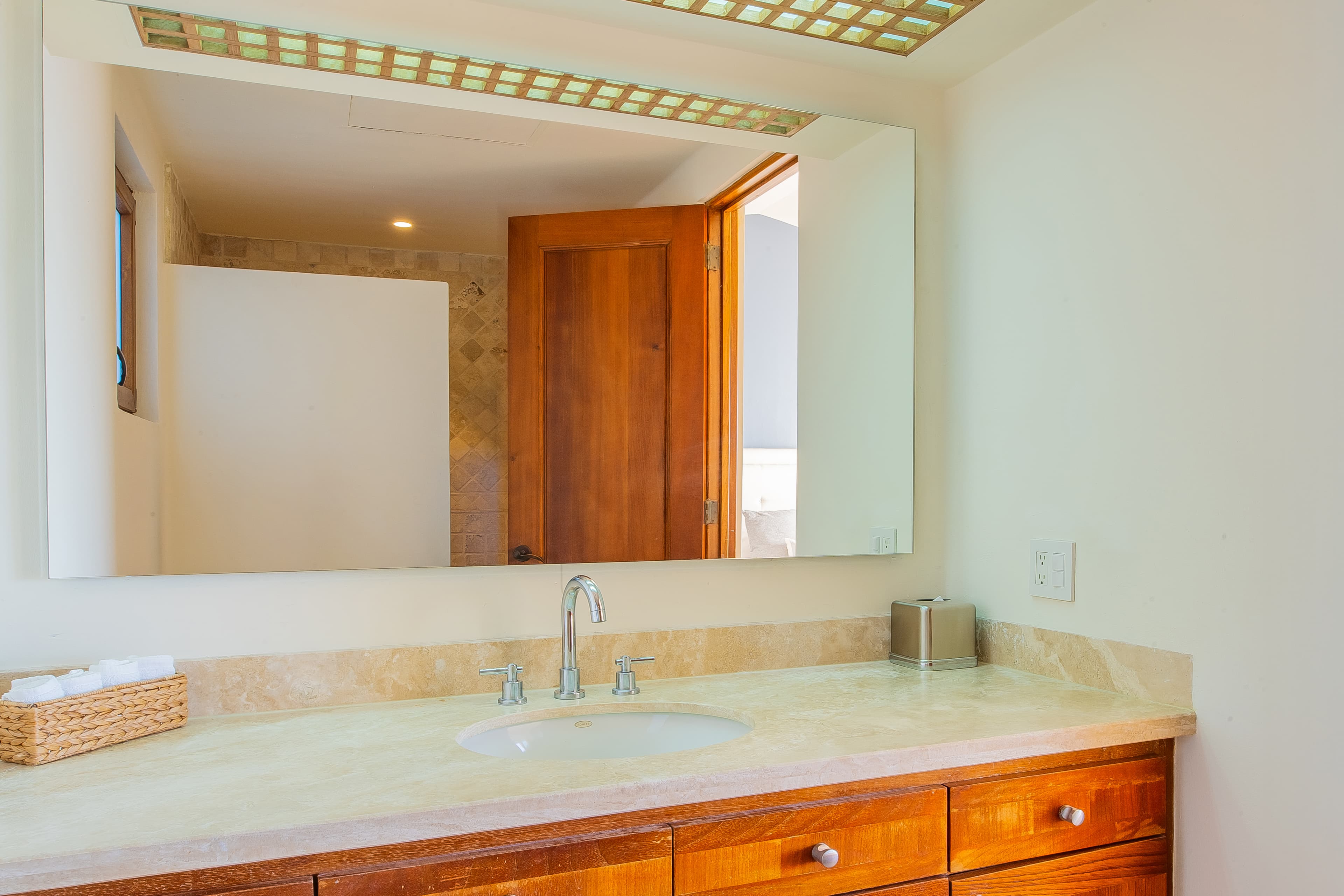 Bathroom 5 · Fresh towels await you in this bright bathroom with warm wood cabinetry, polished stone counters, and a skylight that fills the space with natural light.