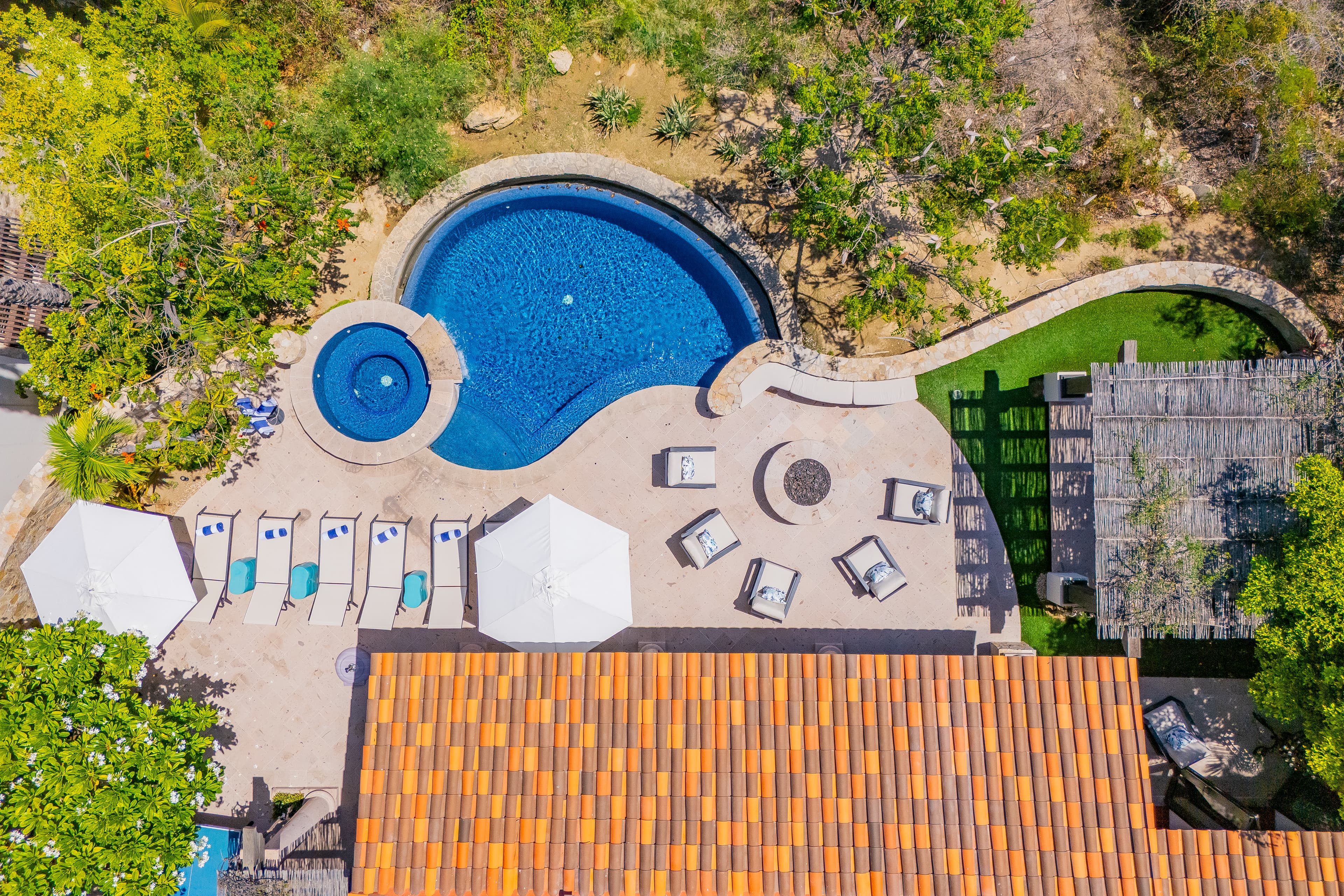 Aerial view of the property's resort-style pool complex, complete with a circular splash pool, sunbeds, and lush Mediterranean gardens—an inviting outdoor retreat.