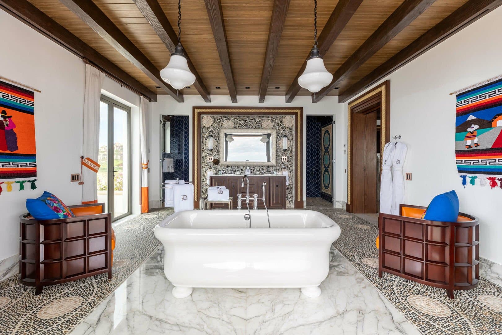 A large standing tub in the middle of the master bathroom, with chairs flanking it on either side.
