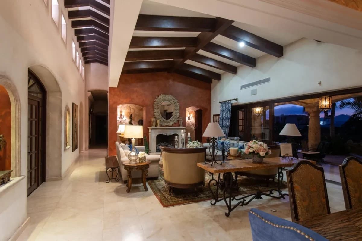 Step into your elegant living room featuring soaring exposed-beam ceilings, a warm fireplace, and handcrafted furnishings perfect for unwinding after a day of exploration.