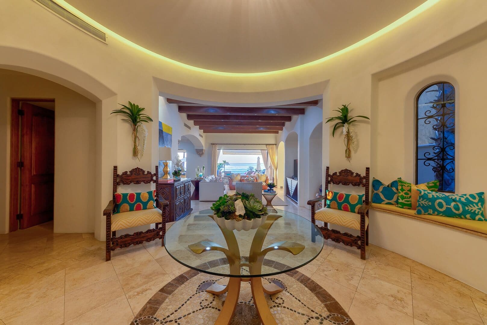 Large entry way with glass table and benches and chairs for seating.