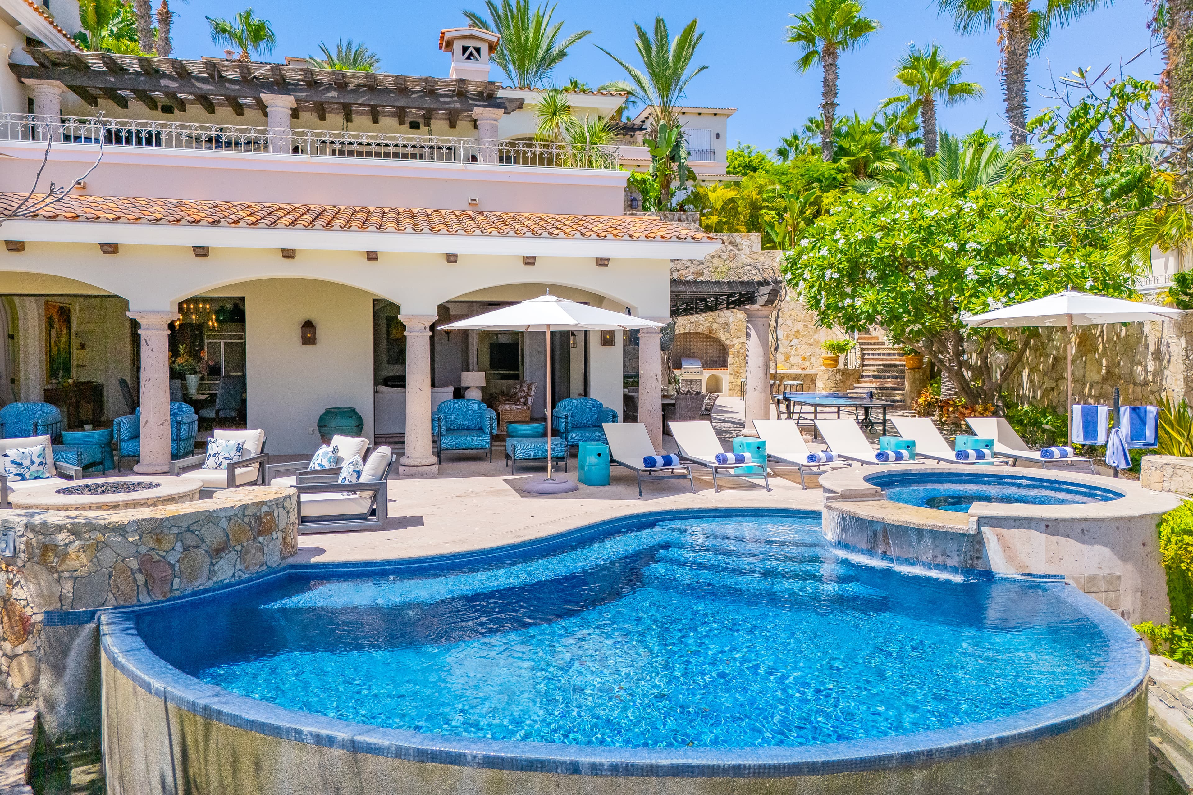 Bask in your private oasis with a sparkling pool and hot tub, surrounded by palms and plush lounge chairs under the warm sun. Your perfect retreat awaits.