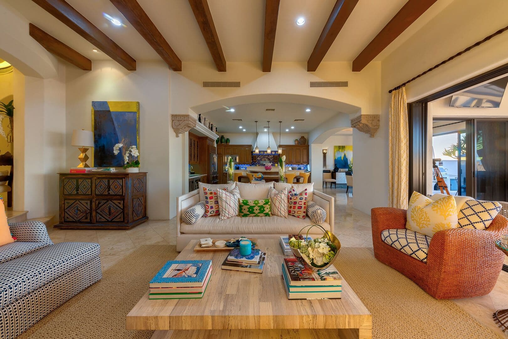 View from the fireplace of the seating area and kitchen behind it.