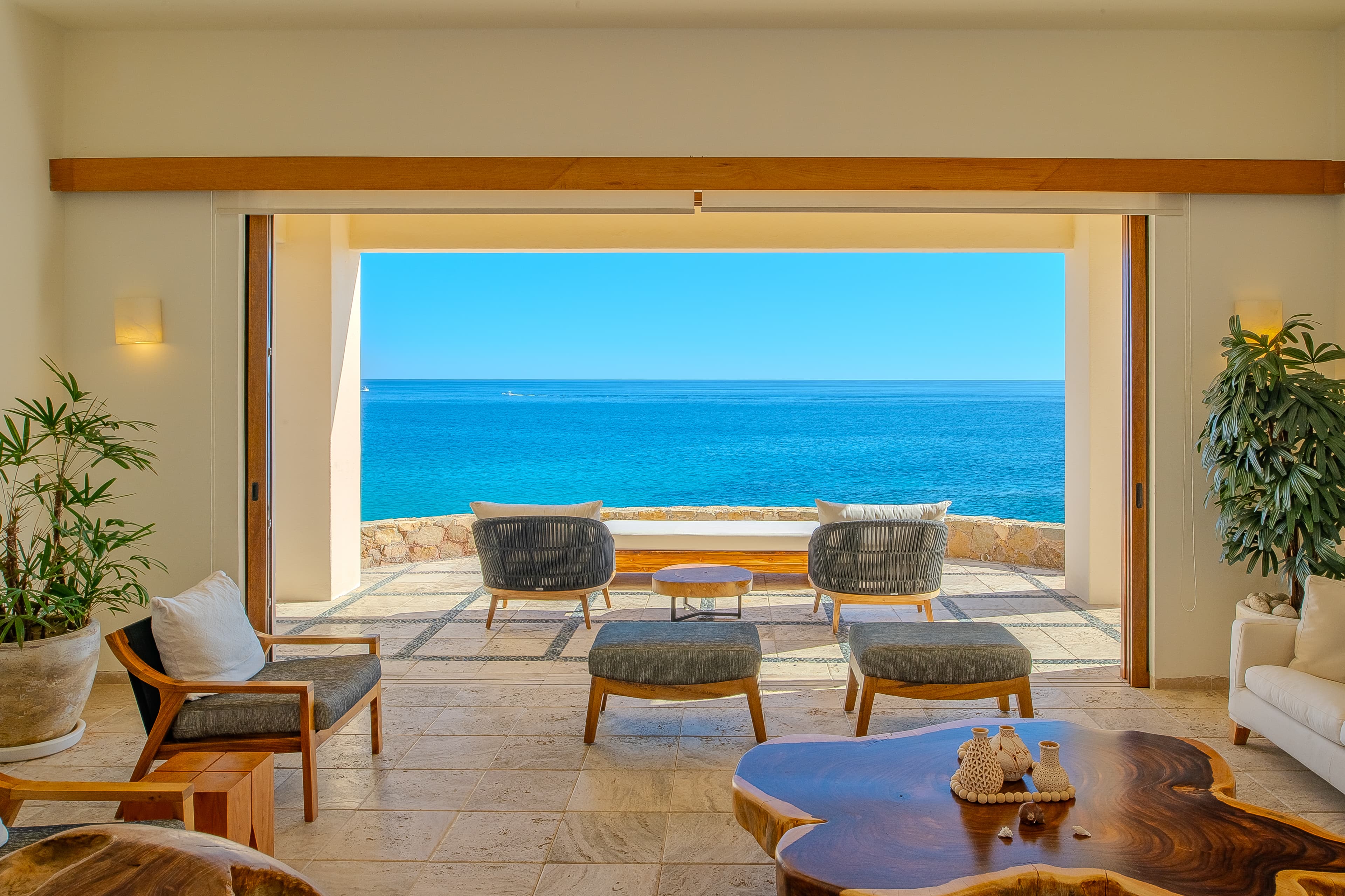 Picture yourself in this serene living space where warm wood tones and soft textures meet breathtaking ocean views. Your private patio invites relaxation with lush greenery framing endless blue horizons.