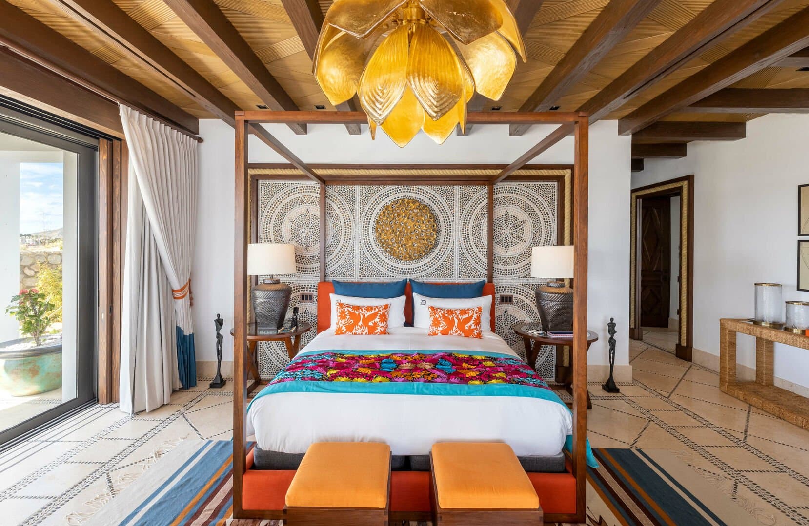 The master bedroom of La Datcha, with a colorful bed centered in the room below a unique chandelier.