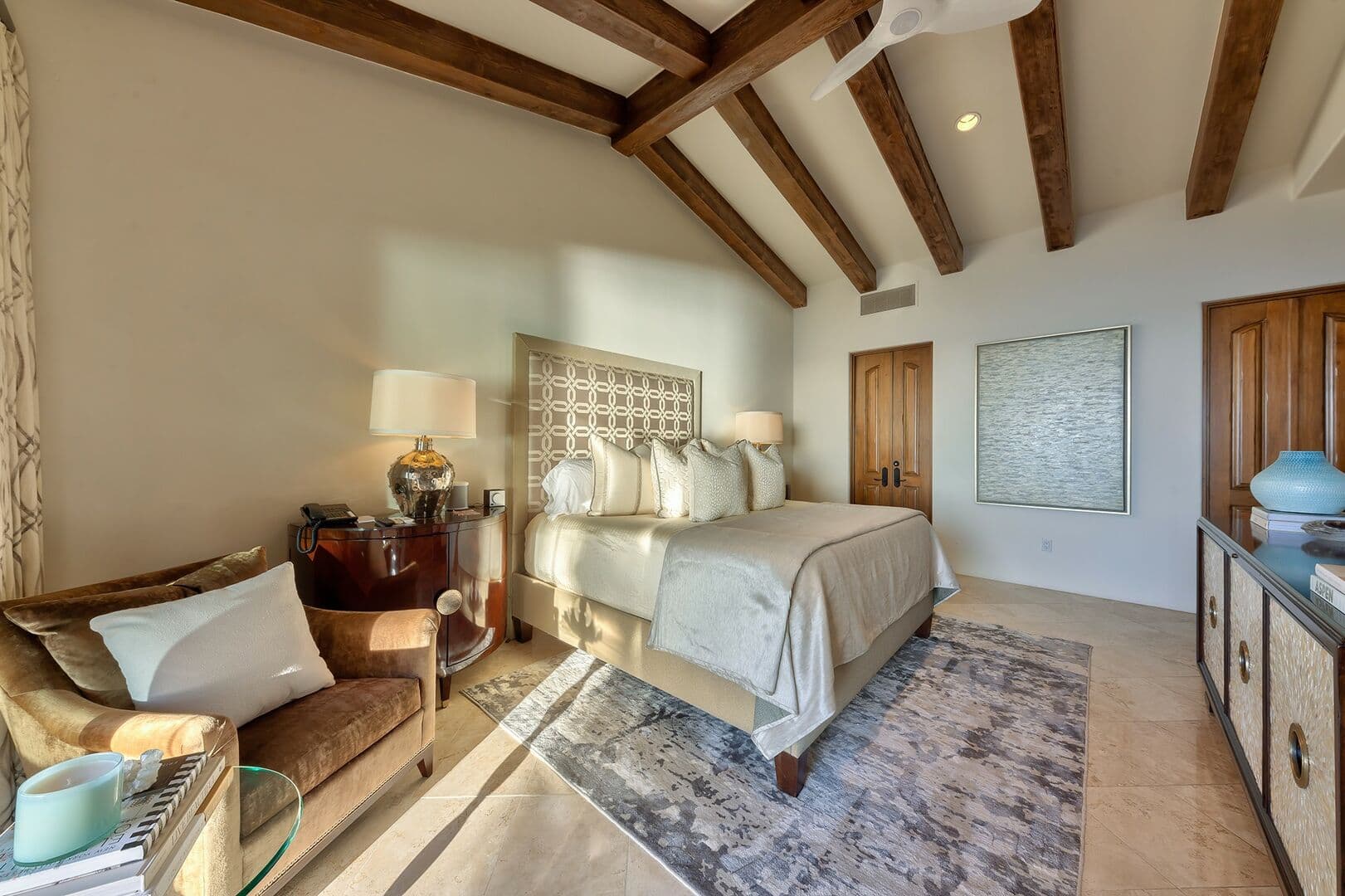 View of bedroom 2 from the balcony with seating in the corner and a large console table.