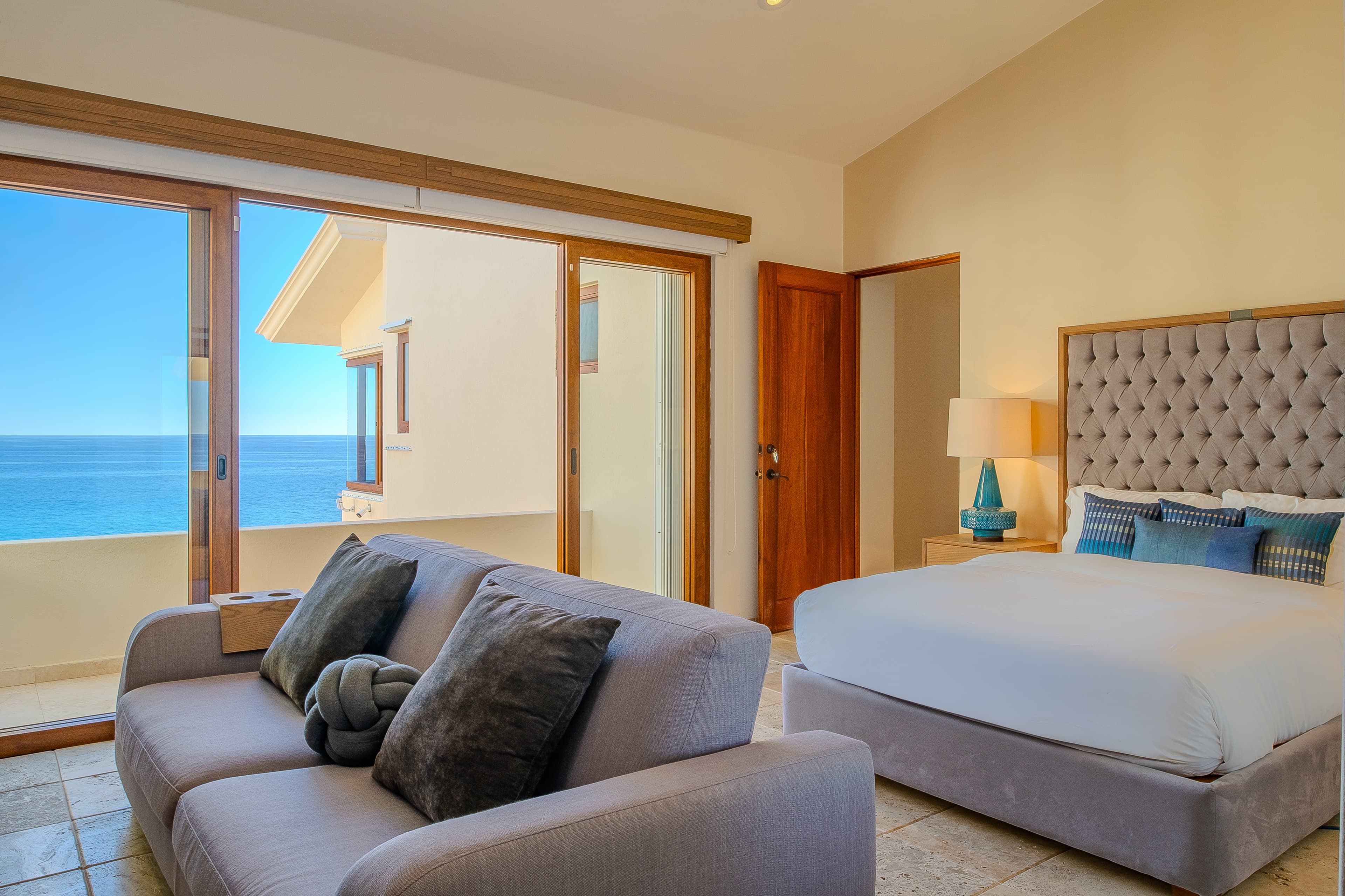 Bedroom 3 · Wake up to stunning ocean vistas through your floor-to-ceiling windows, where plush bedding and a cozy lounge area invite you to unwind while soaking in the endless blue horizon.