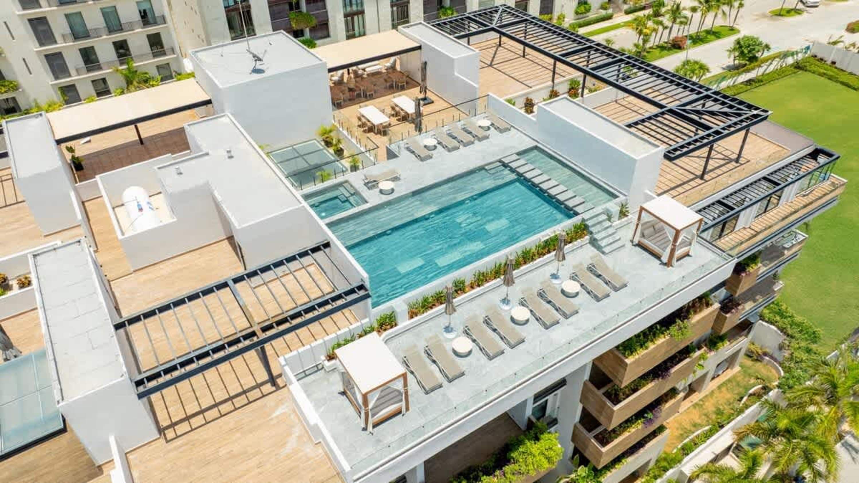 Rooftop pool and lounge area with lounge chairs and umbrellas, overlooking the ocean.