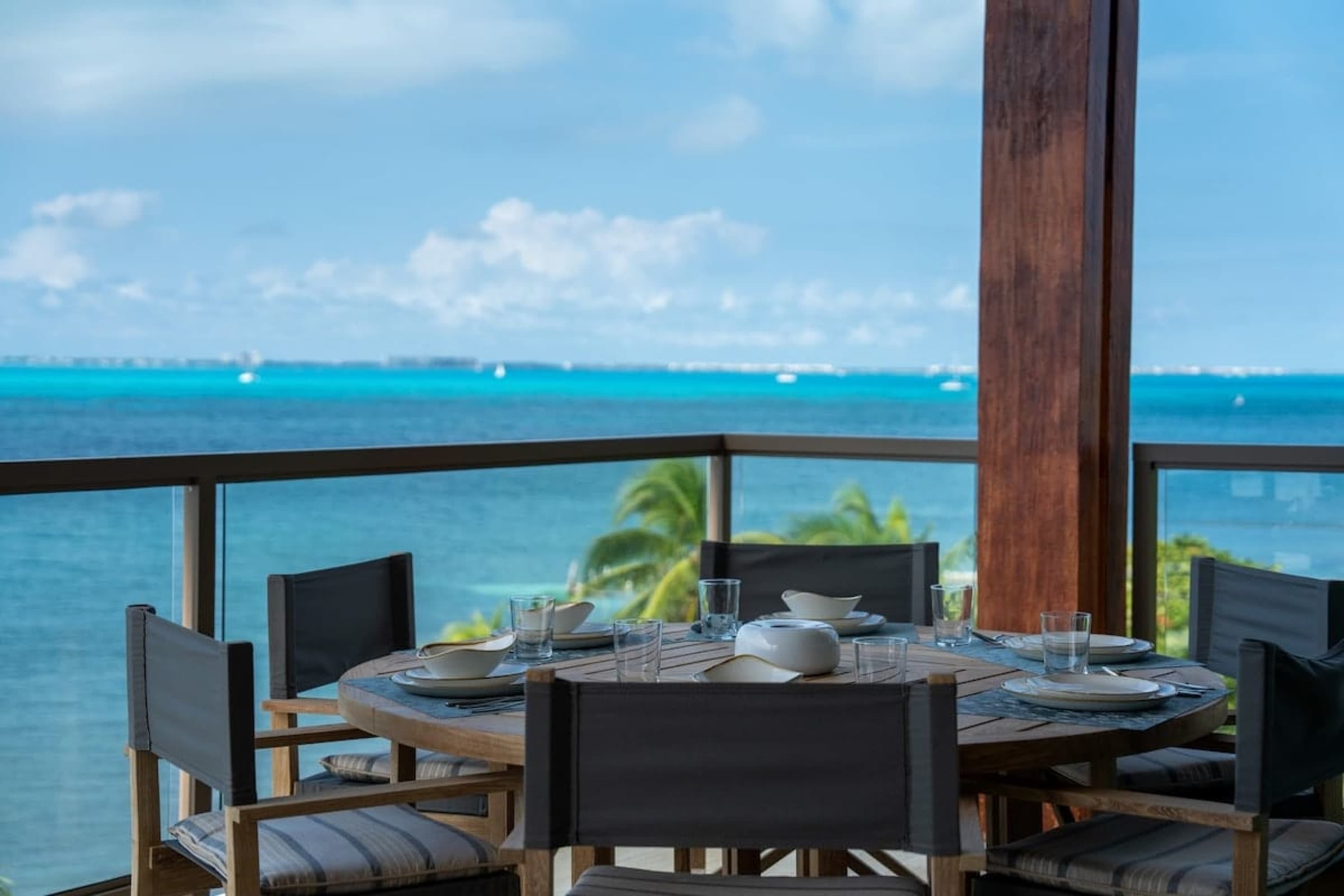 A table set for dining on a balcony overlooking the ocean.