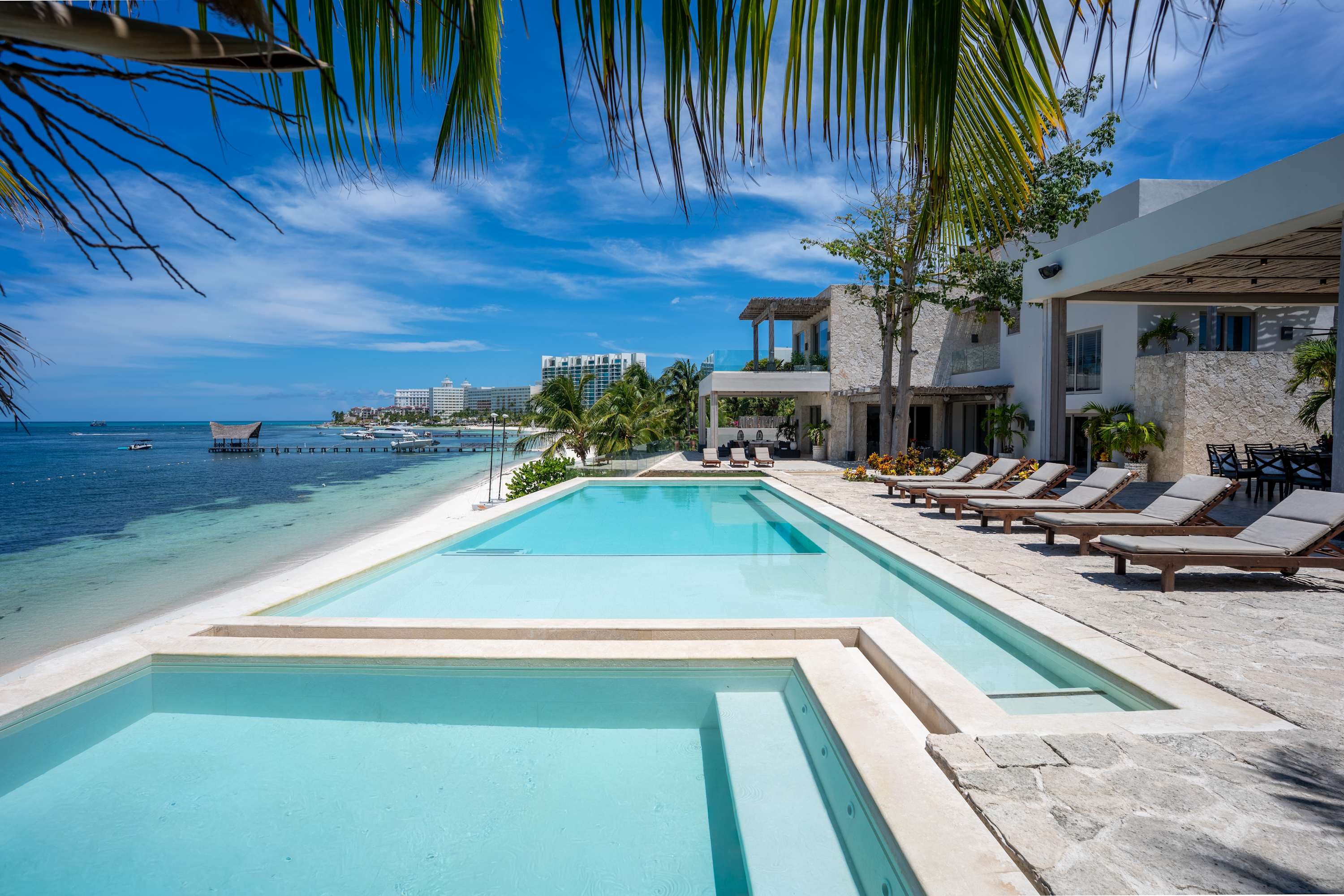Tropical resort with infinity pool, beach, ocean, and hotels.